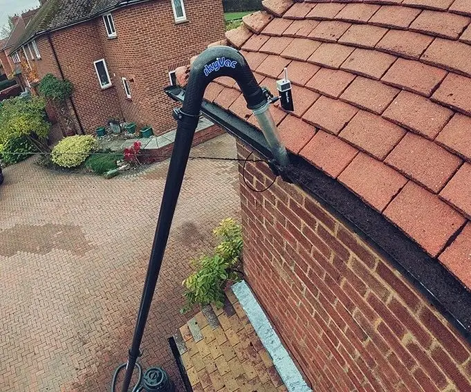 Gutter vacuum pole reaching up to a roof line